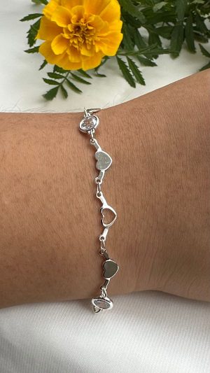 Pulseira feminina com coração liso e vazado conectados com pontos de luz redondo